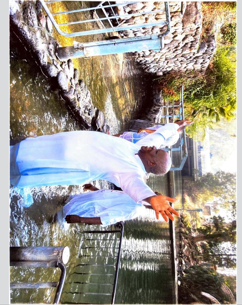 Apostle Odeneye with raised hands in the River Jordan