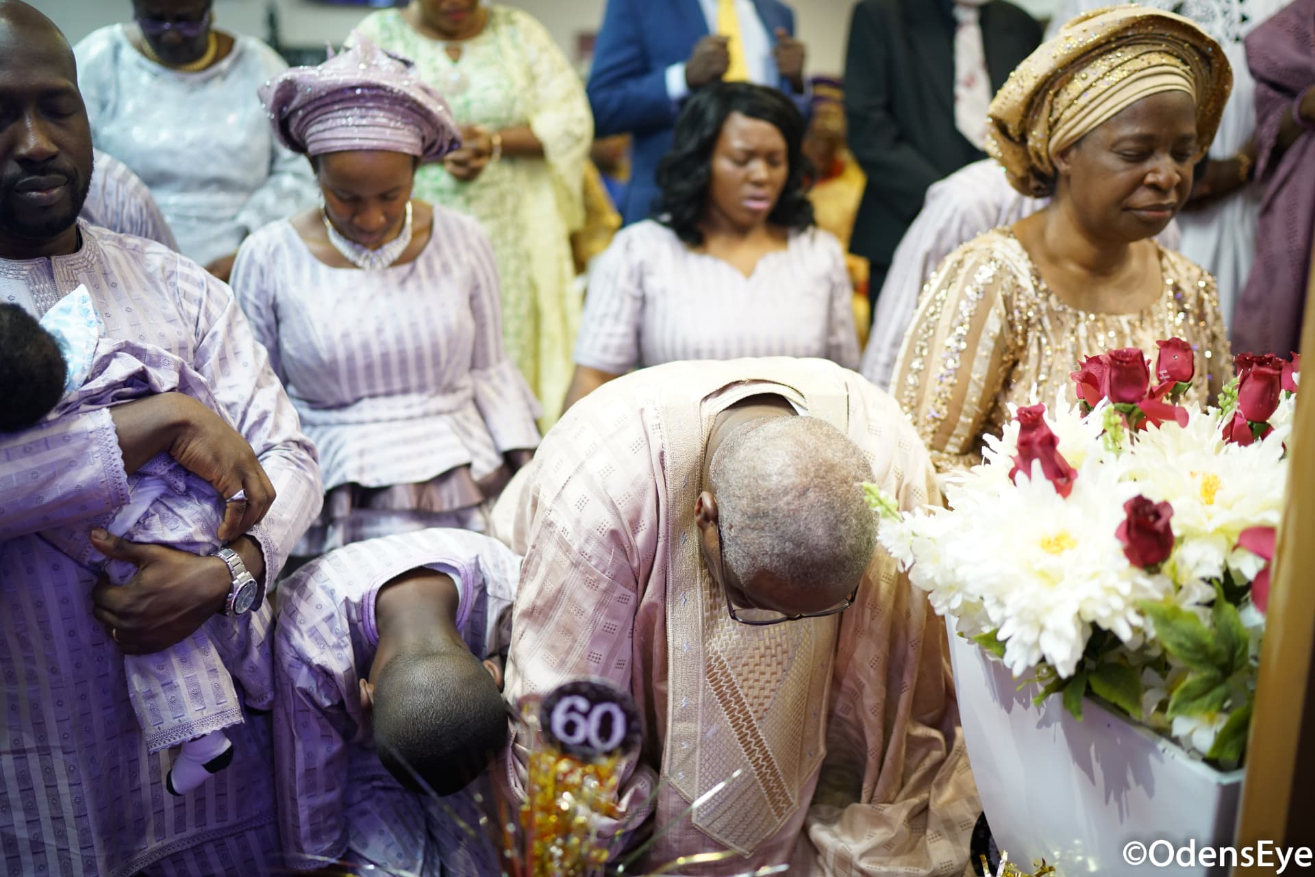 Apostle Odeneye bowed in prayer beside the celebration flowers